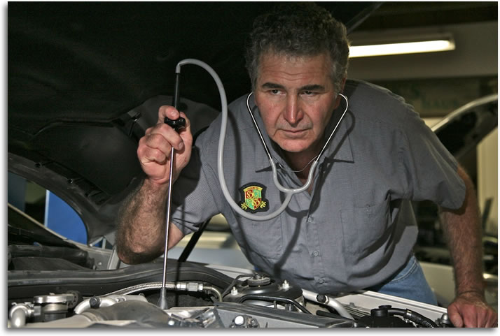 Haik listening to engine noises during car inspection